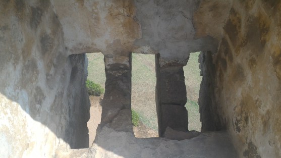 Bobby showing the boys the slits in the outside wall were projectiles could have been shot or oil poured down on any attackers.